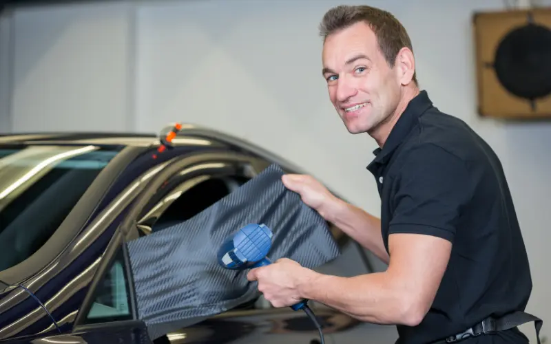 Professional car wrap installation using carbon fibre vinyl, demonstrating how vinyl car wraps are applied to vehicle panels in the UK