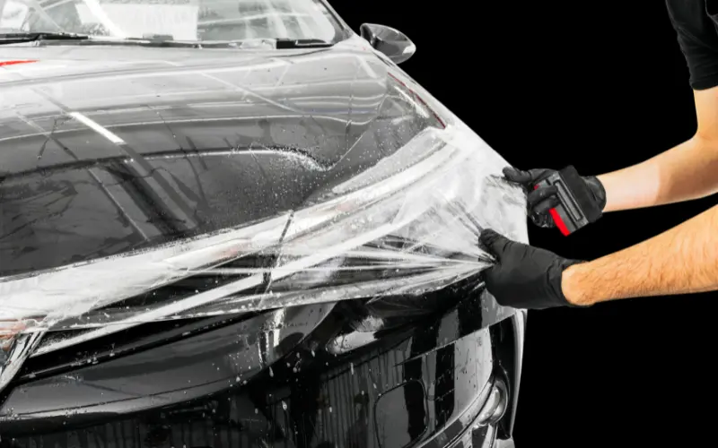 Paint protection film being applied to a car bonnet, showing how vinyl wrap protects car paint from stone chips and road damage