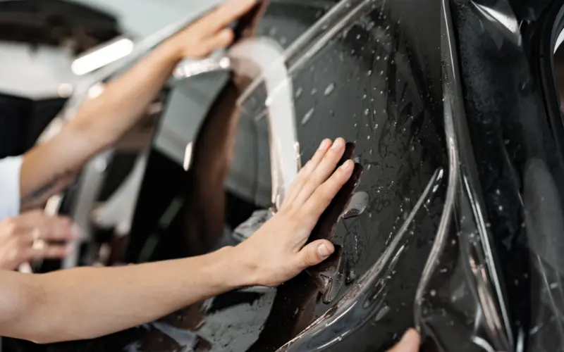 Do Car Wraps Damage Paintwork? The Truth About Vinyl Wrap Effects 1 Professional vinyl car wrap installation on a vehicle door, demonstrating proper application techniques used to protect factory paint.