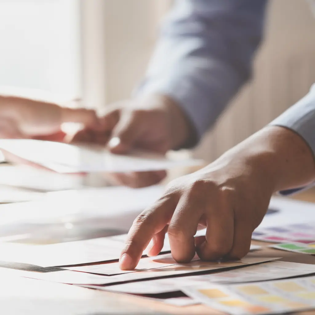 Difference Between Flyers and Brochures Explained 2 Graphic designer reviewing brochure layouts and flyer designs, highlighting the difference between brochures and flyers for business marketing.