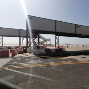 Temporary hoarding construction gantry with concrete safety barriers controlling vehicle and pedestrian access on a development site