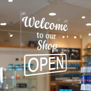 Clear acrylic shop door sign with white vinyl text reading Welcome to our Shop and Open